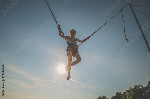 active child in bungee jumping trampoline at sunset