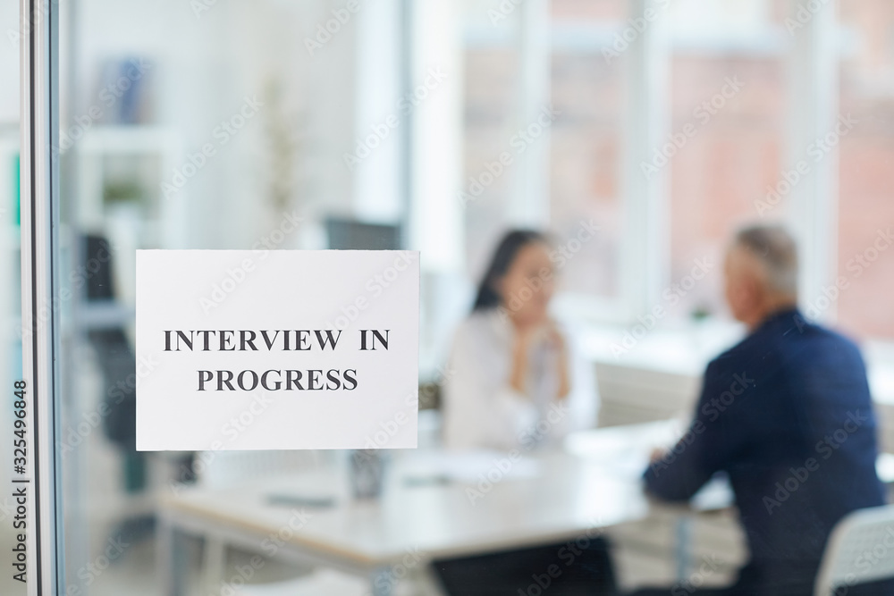 Background image of job interview in progress sign on glass door in