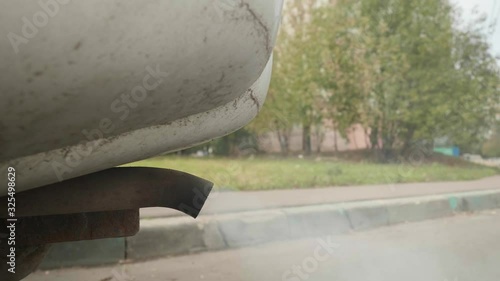 Close up of exhausts coming from pipe of car with incorrect functioning of ICE engine. Frog veye view. photo