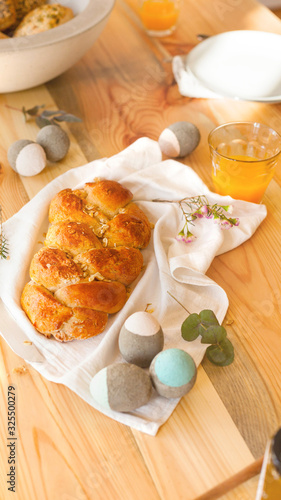 Easter table laid for Easter breakfast Easter Sunday in sunlight orange juice and Easter braid pastries interior decoration concrete Easter eggs natural and sustainable decoration