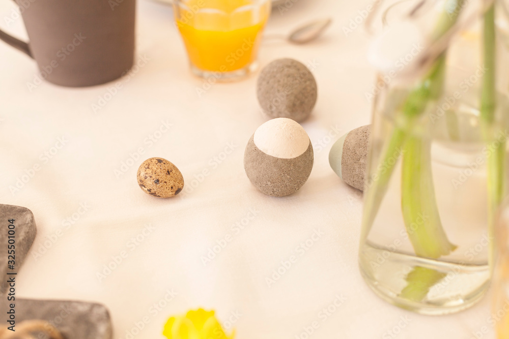 white tablecloth laid on easter table for easter breakfast orange juice and narcissus flowers interior decoration concrete easter eggs natural and sustainable decoration