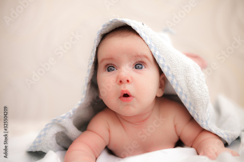 baby boy is surprised and lies on his stomach in a towel with ears after bathing