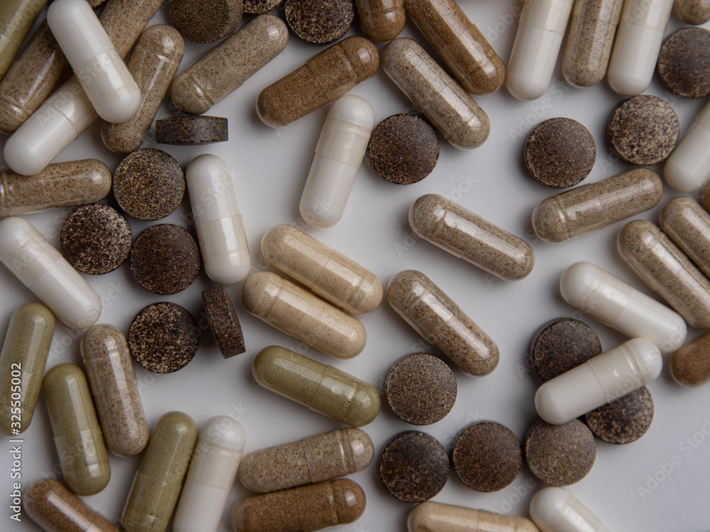 many different pills and capsules on a white table, top view many different pills and capsules on a white table, top view