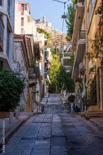 Fototapeta Naklejka Na Ścianę i Meble -  Narrow street scene in Athens with a view of filopappou hill
