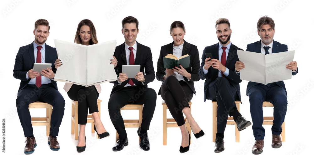 Team of 6 reading from book, phone, tablets and newspapers