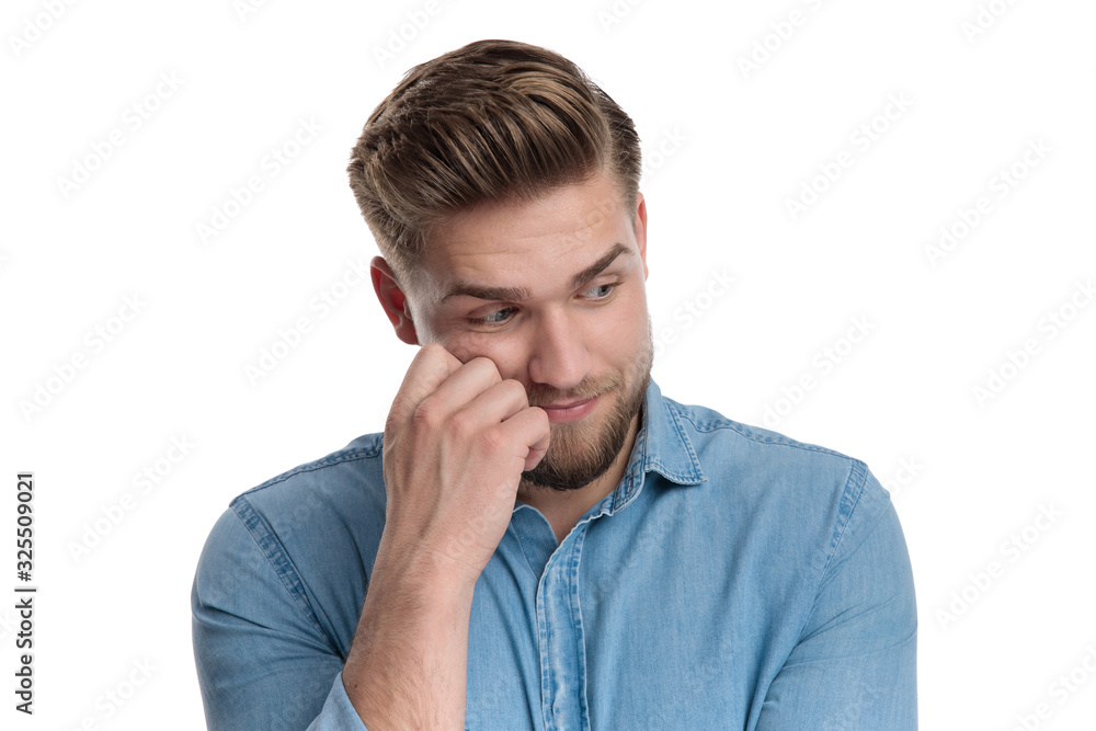 Wondering casual man looking away with hand on his face Wondering casual man looking away with hand on his face
