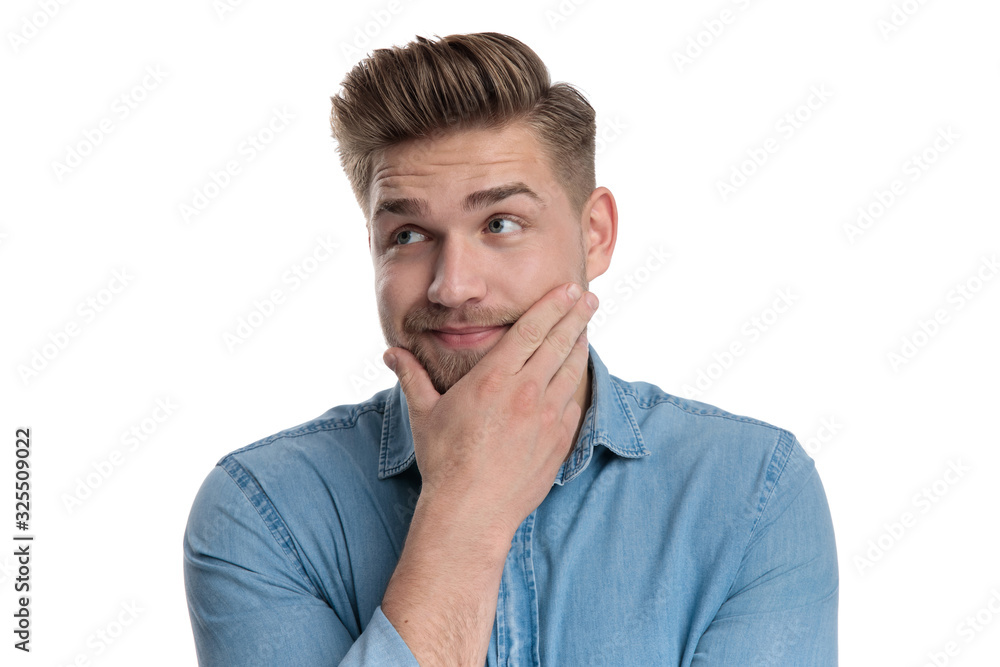 Dreaming casual man looking away with hand on chin