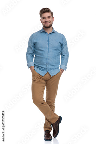 Happy casual man holding both hands in his pockets