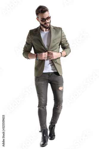 Confident fashion model unbuttoning his jacket and looking away