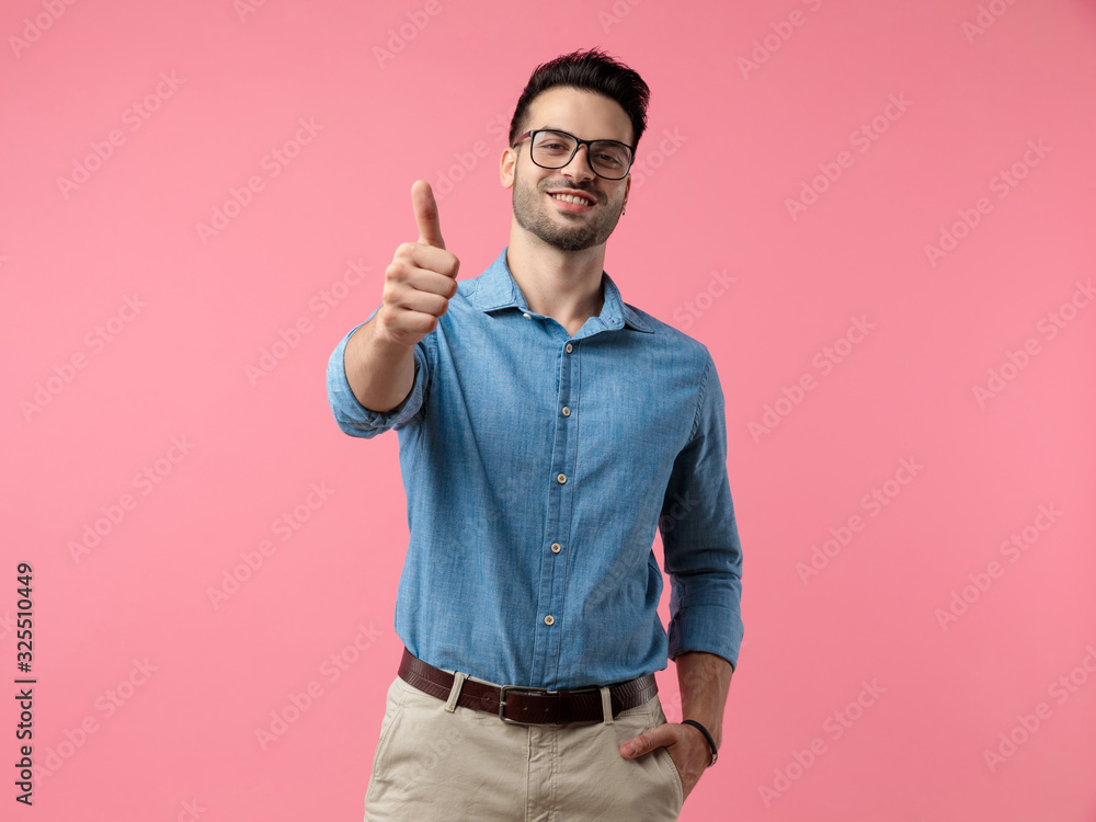 young casual man smiling and making thumbs up sign young casual man smiling and making thumbs up sign