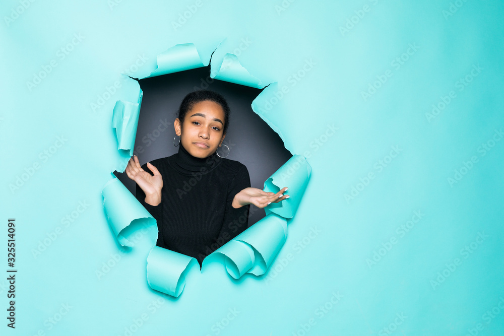 Young smile latin woman posing from green paper hole Young smile latin woman posing from green paper hole