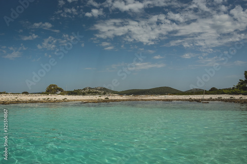 Tourquise coastal panorama of a croatian island, looking from the water towards the shore. Summer feeling and rocky beach.