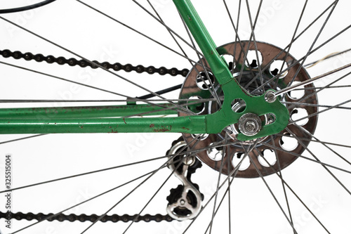 An old retro looking green vintage city bicycle for women, isolated o white background. Closeup or detail of rear hub, deraileur, casette and chain. Axle with nut is visible.