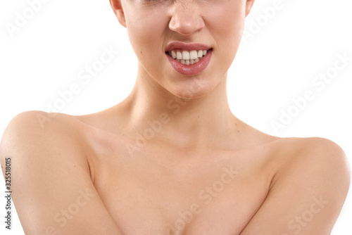 Showing her teeth. Cropped photo of young half-naked blond woman with short hair snarling at the camera while standing against white background