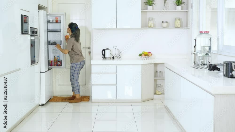 Cheerful woman take an apple and dance in kitchen Cheerful woman take an apple and dance in kitchen