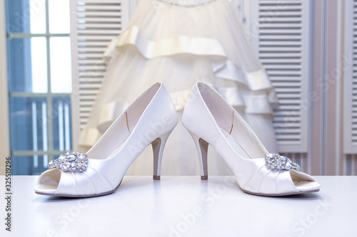 Wedding white shoes in the foreground and a wedding dress. Holiday