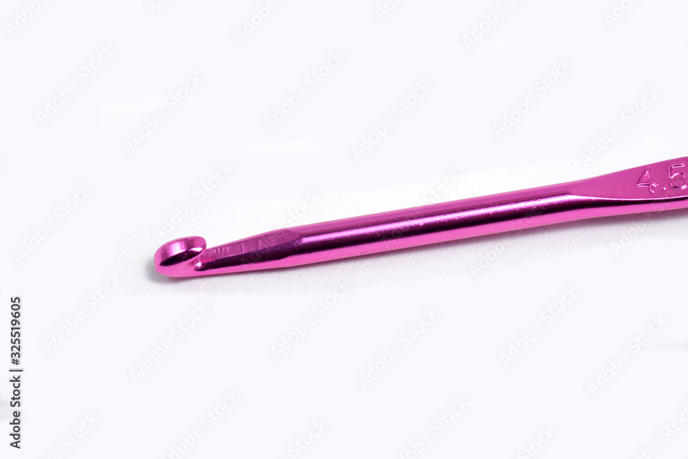 Pink metal crochet hook for knitting craft on an isolated white background Pink metal crochet hook for knitting craft on an isolated white background