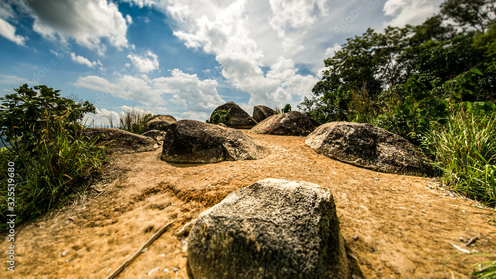 On the top of Broga Hill, Selangor, Malaysia. On the peak of the mountain, during a hiking tour. Rocks are in the way. Yellow soil under blue sky on a hot day at south east Asia. Truly Asia  