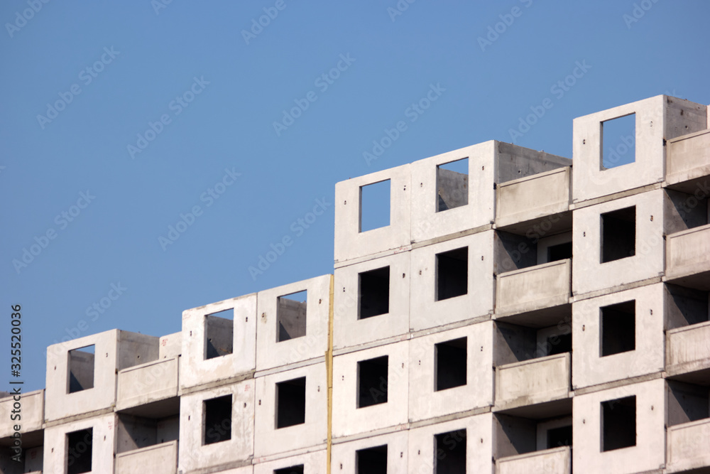 Unfinished skyscraper under construction. Cement building, blue sky background. Unfinished skyscraper under construction. Cement building, blue sky background.