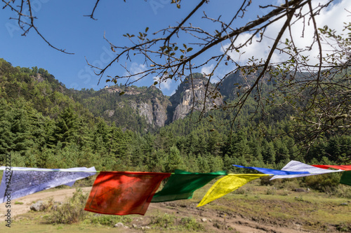 Buddhism Prayer flags waving in the wind on the hiking trail to the tiger nest in Bhutan, Himalaya. Blue sky behind the mountains of Bhutan.