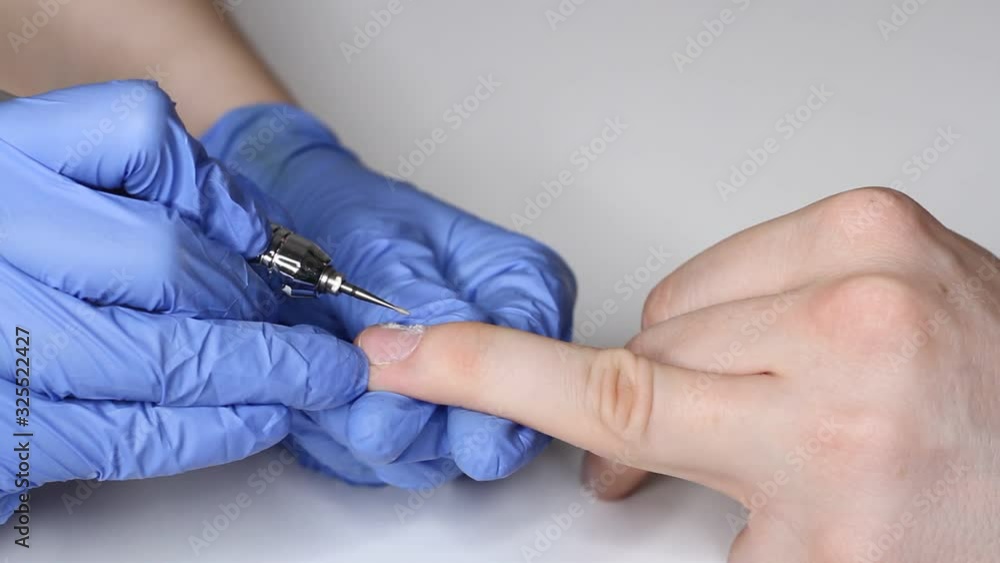 Manicurist in the salon in blue gloves makes a manicure for a man. Manicurist in the salon in blue gloves makes a manicure for a man.