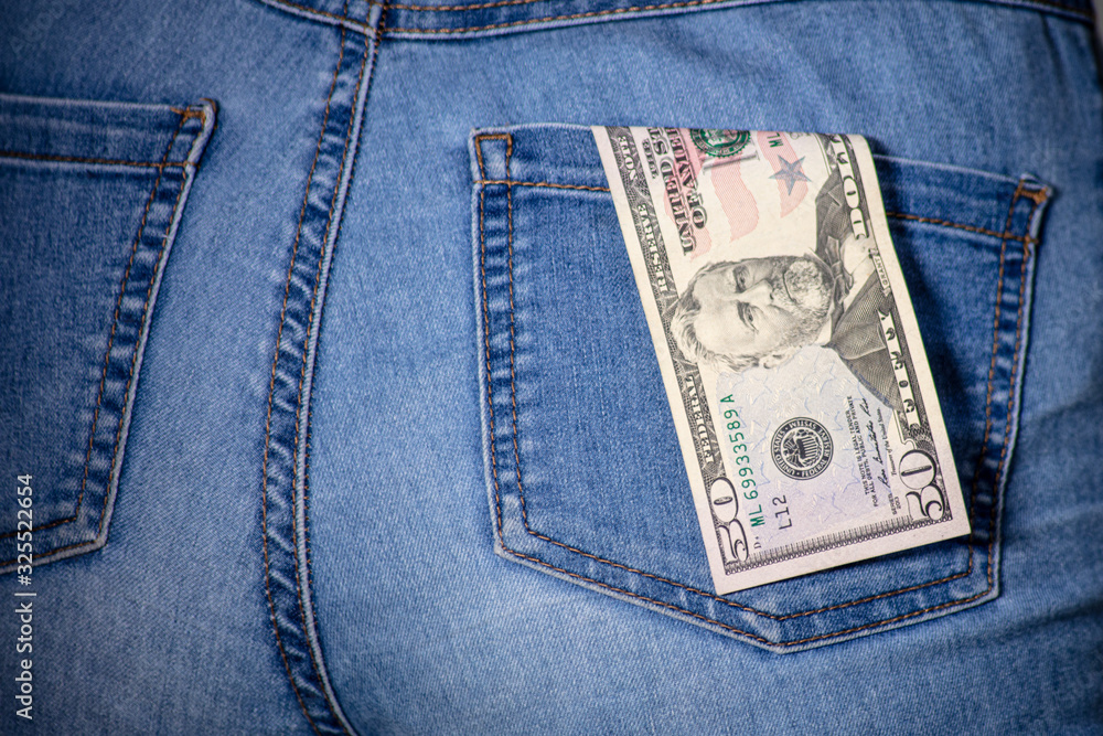 50 dollars in a female jeans pocket. American fifty dollar notes stuck