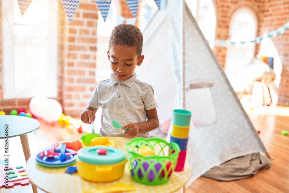 Beautiful african american toddler playing with plastic food and cutlery toy at kindergarten Beautiful african american toddler playing with plastic food and cutlery toy at kindergarten