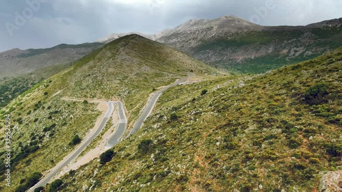 Breathtaking aerial view of tiny curvy roads on majestic huge mountains, under the cloudy sky. photo
