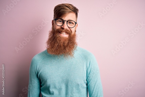 Handsome Irish redhead man with beard wearing glasses over pink isolated background with a happy and cool smile on face. Lucky person.