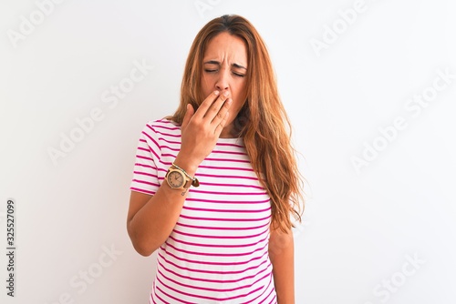 Young redhead woman wearing striped casual t-shirt stading over white isolated background bored yawning tired covering mouth with hand. Restless and sleepiness.