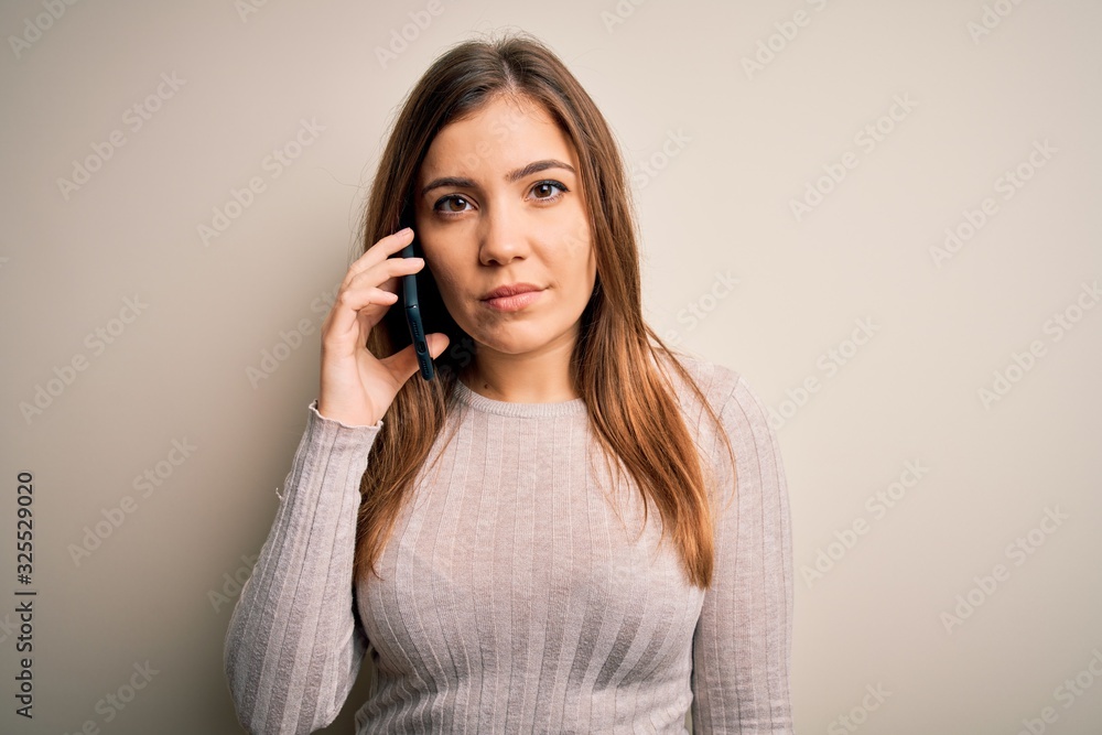 Young woman having a conversation speaking on smartphone over isolated background with a confident expression on smart face thinking serious Young woman having a conversation speaking on smartphone over isolated background with a confident expression on smart face thinking serious