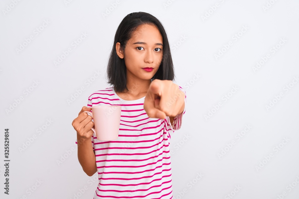 Young beautiful chinese woman drinking cup of coffee over isolated white background pointing with finger to the camera and to you, hand sign, positive and confident gesture from the front Young beautiful chinese woman drinking cup of coffee over isolated white background pointing with finger to the camera and to you, hand sign, positive and confident gesture from the front