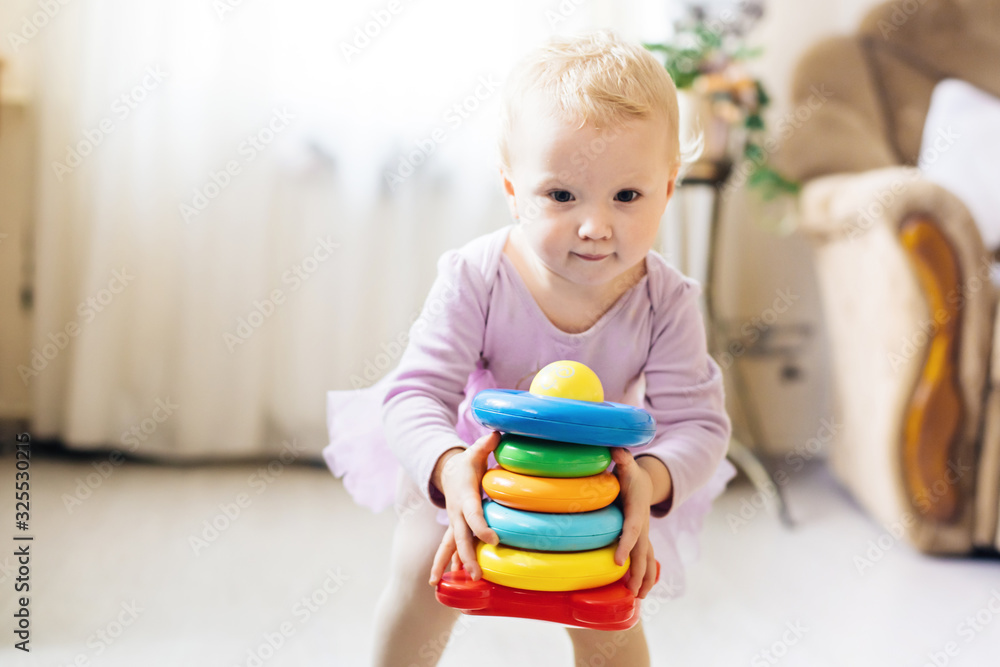 girl plays logical pyramid on floor in living room on sunny day. girl plays logical pyramid on floor in living room on sunny day.