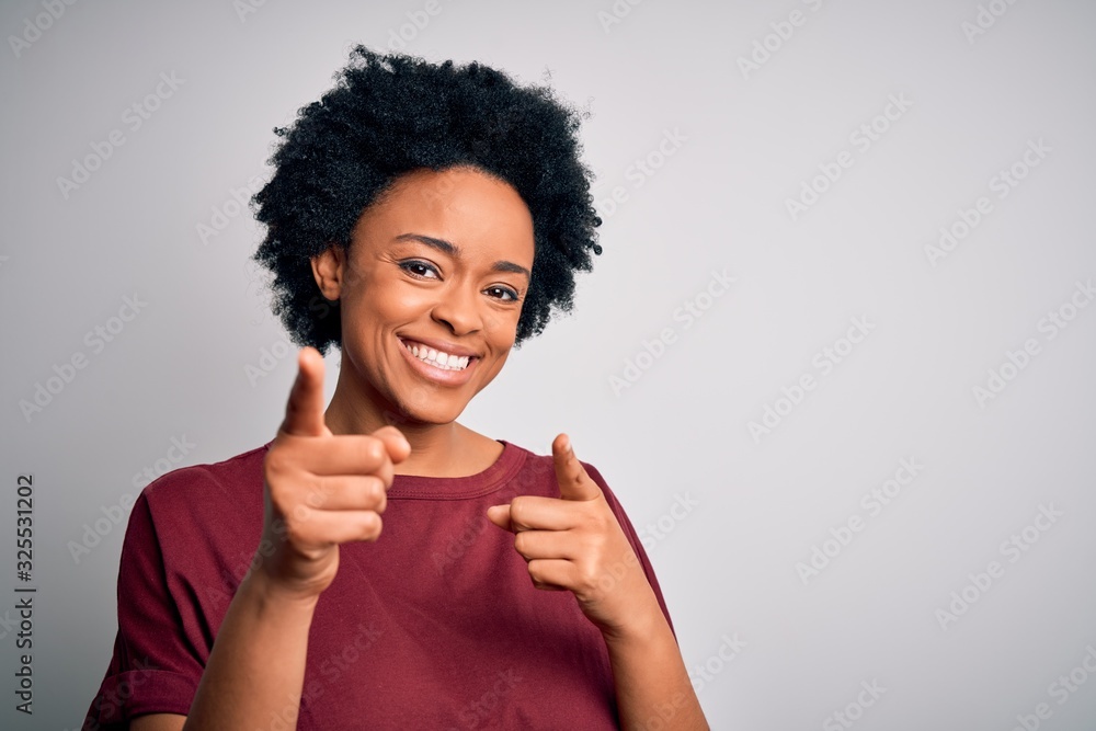 Young beautiful African American afro woman with curly hair wearing casual t-shirt standing pointing fingers to camera with happy and funny face. Good energy and vibes. Young beautiful African American afro woman with curly hair wearing casual t-shirt standing pointing fingers to camera with happy and funny face. Good energy and vibes.