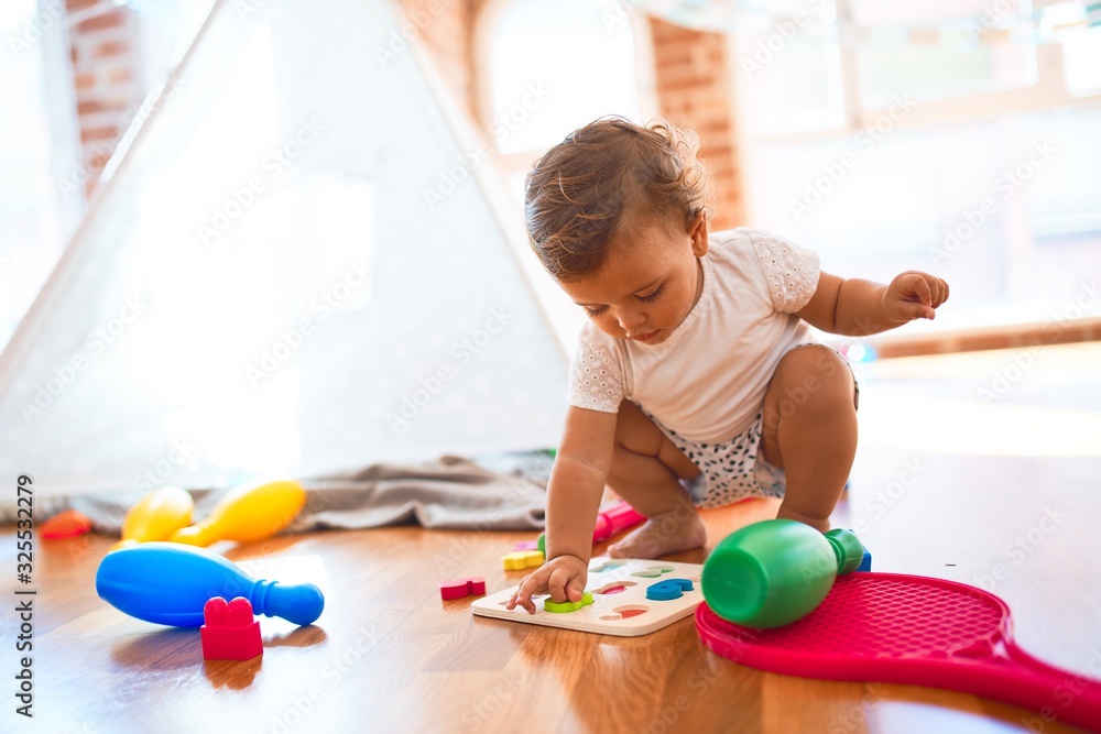 Adorable toddler learning numbers using maths puzzle around lots of toys at kindergarten Adorable toddler learning numbers using maths puzzle around lots of toys at kindergarten