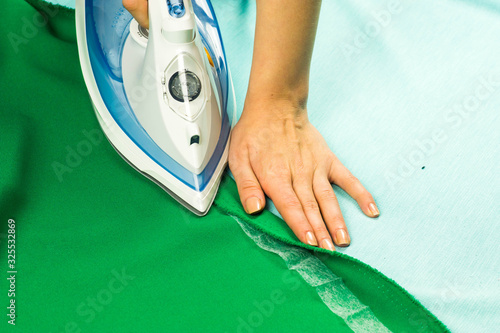 Obraz na płótnie woman hemming, shortening green courtain fabric with an adhesive iron-on hemming tape w salonie