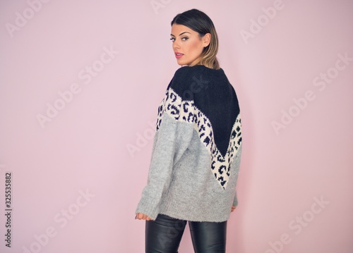 Young beautiful woman wearing fashionable clothes standing over isolated pink background photo