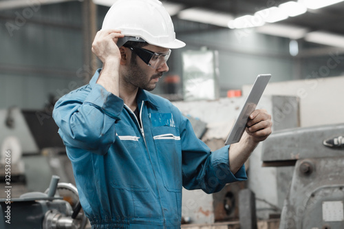 Maintenance engineer industrial plant with a tablet in hand and document plan, Engineer looking of working at industrial machinery setup in factory.