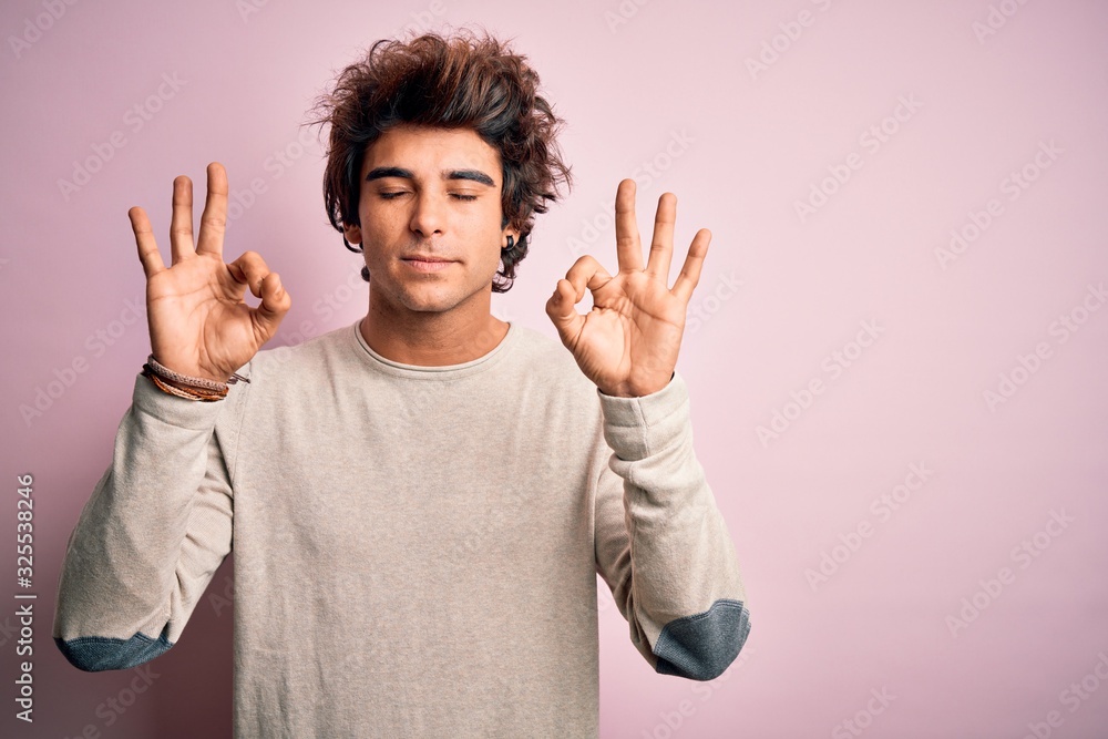 Young handsome man wearing casual t-shirt standing over isolated pink background relaxed and smiling with eyes closed doing meditation gesture with fingers. Yoga concept. Young handsome man wearing casual t-shirt standing over isolated pink background relaxed and smiling with eyes closed doing meditation gesture with fingers. Yoga concept.