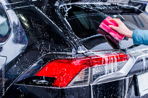 Girl cleaning automobile with sponge at car wash, car washing © FakeMoon