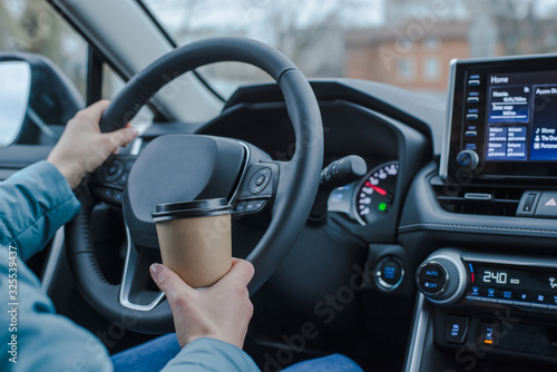 Close up young girl car driver drink coffee, hand holding a Paper Cup of coffee. Travel with coffee.  Concept of coffee with you. Mockup © FakeMoon