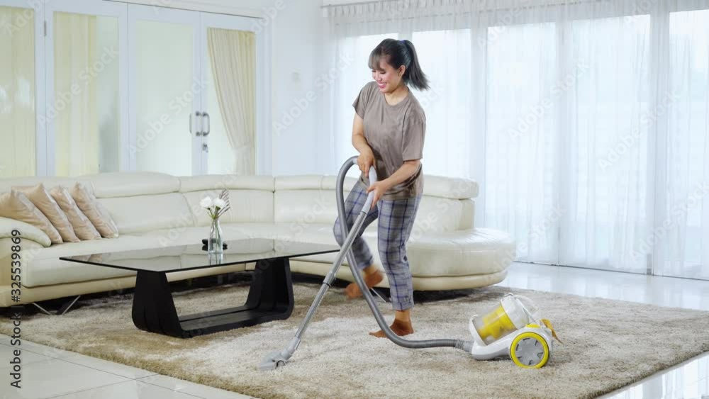 Happy woman cleaning carpet while dancing at home Happy woman cleaning carpet while dancing at home