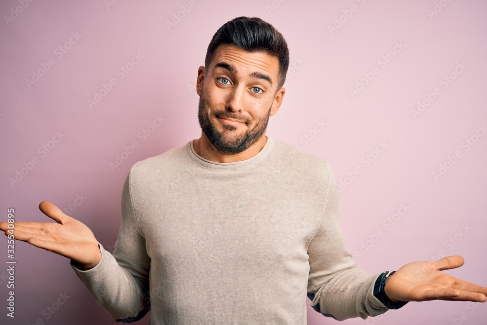 Young handsome man wearing casual sweater standing over isolated pink background clueless and confused expression with arms and hands raised. Doubt concept. Young handsome man wearing casual sweater standing over isolated pink background clueless and confused expression with arms and hands raised. Doubt concept.