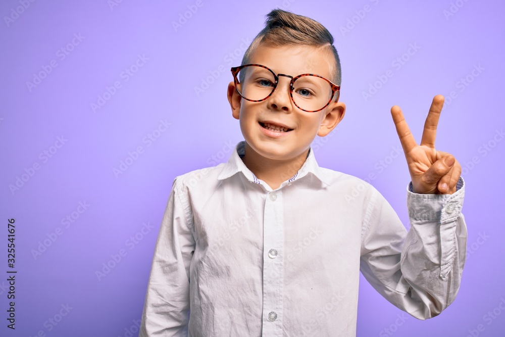 Young little caucasian kid with blue eyes wearing glasses and white shirt over purple background smiling with happy face winking at the camera doing victory sign. Number two. Young little caucasian kid with blue eyes wearing glasses and white shirt over purple background smiling with happy face winking at the camera doing victory sign. Number two.