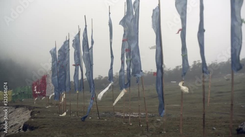 Buddhist prayer flags blow in strong wind, Medium shot, pan left photo