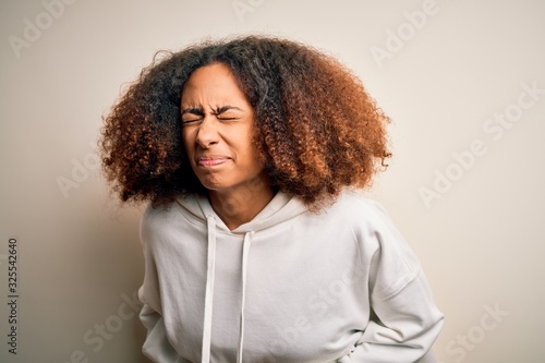 Young african american sportswoman with afro hair wearing sporty sweatshirt with hand on stomach because indigestion, painful illness feeling unwell. Ache concept.