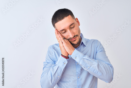 Young handsome business man standing over isolated background sleeping tired dreaming and posing with hands together while smiling with closed eyes.