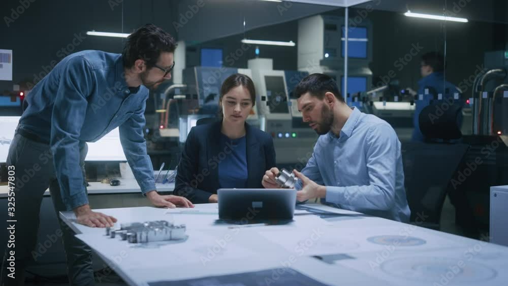 Factory Office Meeting Room: Team of Engineers Gather Around Conference Table, They Discuss Project Blueprints, Inspect Mechanism, Find Solutions, Use Laptop. Industrial Technology Factory