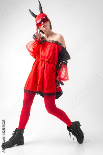 Sexy devil girl in red tights and black boots posing on white studio background.