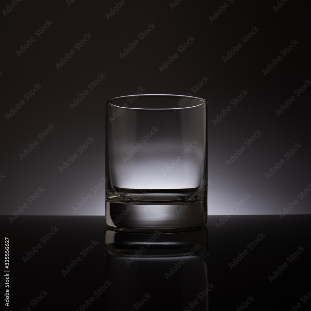 Empty transparent glass on a dark background, reflected from a black surface Empty transparent glass on a dark background, reflected from a black surface